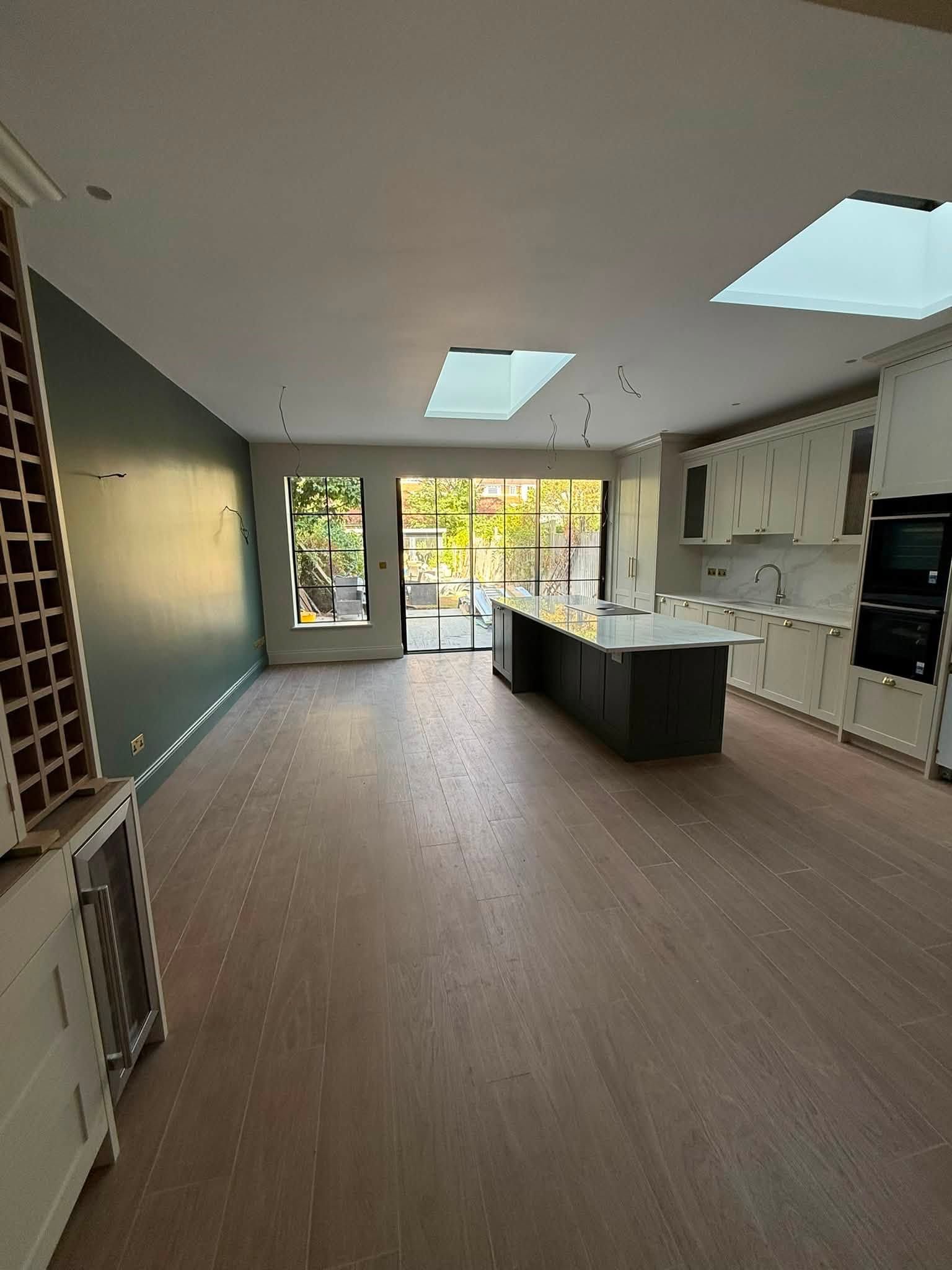 Open-plan kitchen extension with roof lights, a dark kitchen island and steel-framed doors to the garden